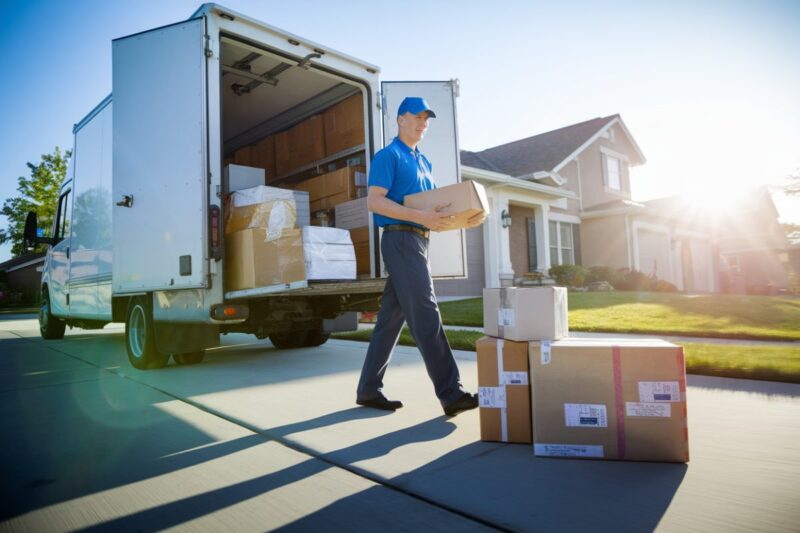 Camion de livraison d&eacute;chargeant des colis devant une maison