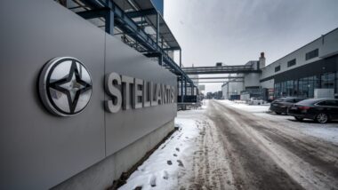 Panneau Stellantis devant un site industriel automobile sous ciel gris