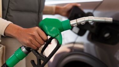 Des automobilistes font la queue à une station-service avec prix affichés