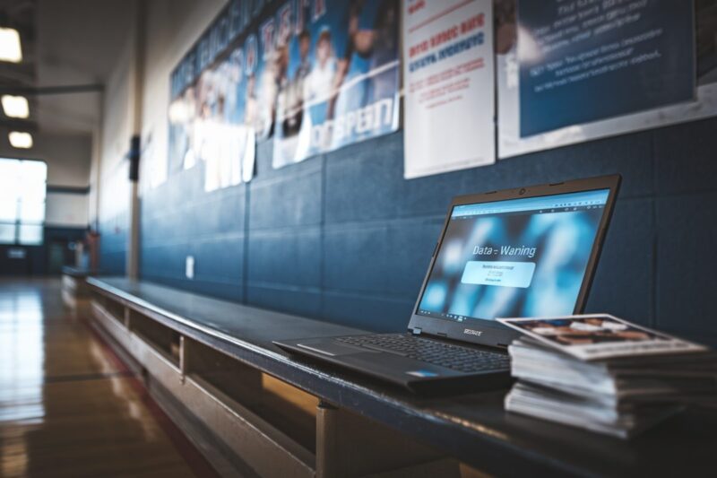 Ordinateur affichant alerte fuite de données dans un gymnase scolaire