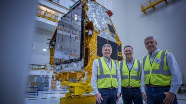 Des ingénieurs observent un satellite en cours d’assemblage dans une salle blanche